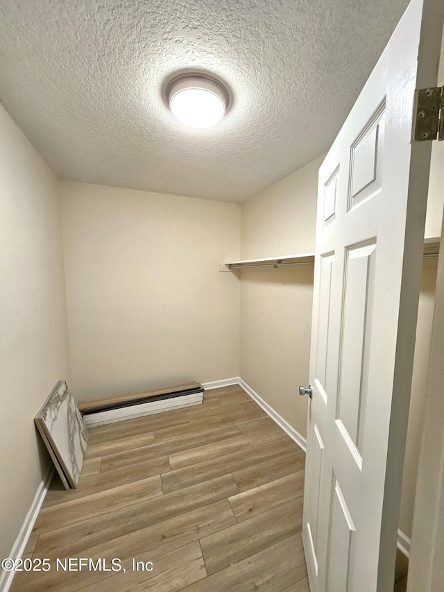 spacious closet featuring wood-type flooring and baseboard heating