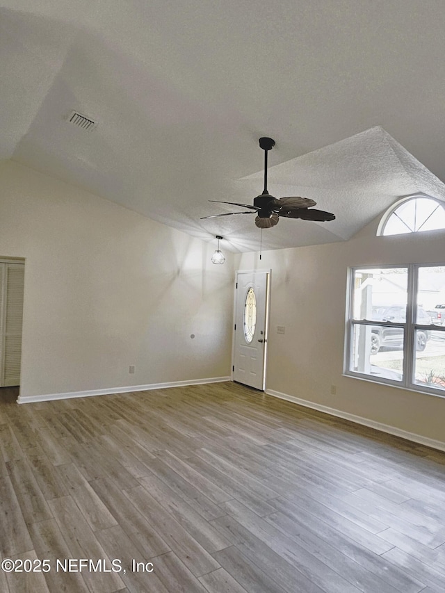 interior space with ceiling fan, light wood-type flooring, a textured ceiling, and lofted ceiling