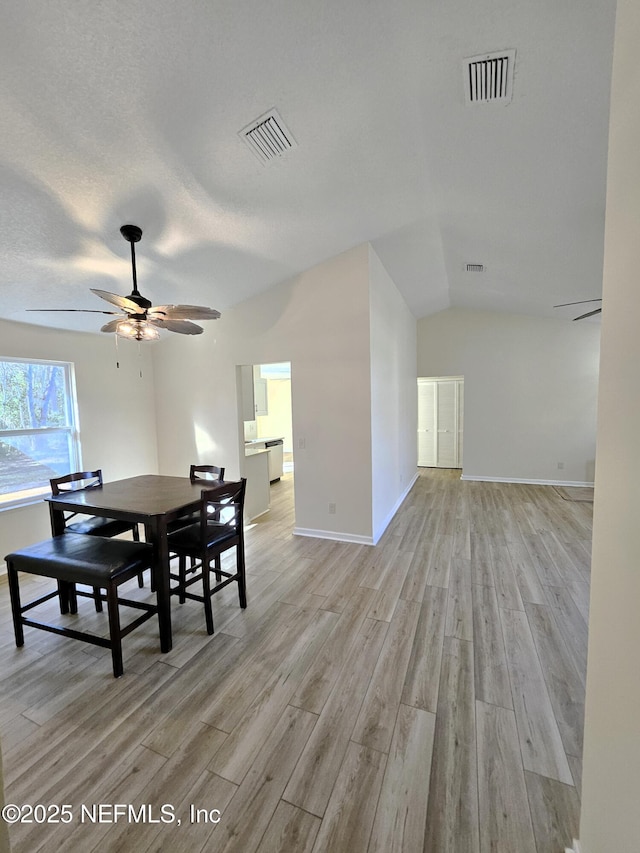 dining room featuring ceiling fan, light hardwood / wood-style floors, and lofted ceiling