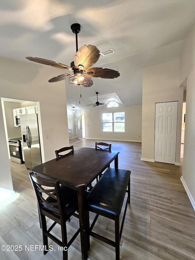 dining room with wood-type flooring, a textured ceiling, ceiling fan, and lofted ceiling