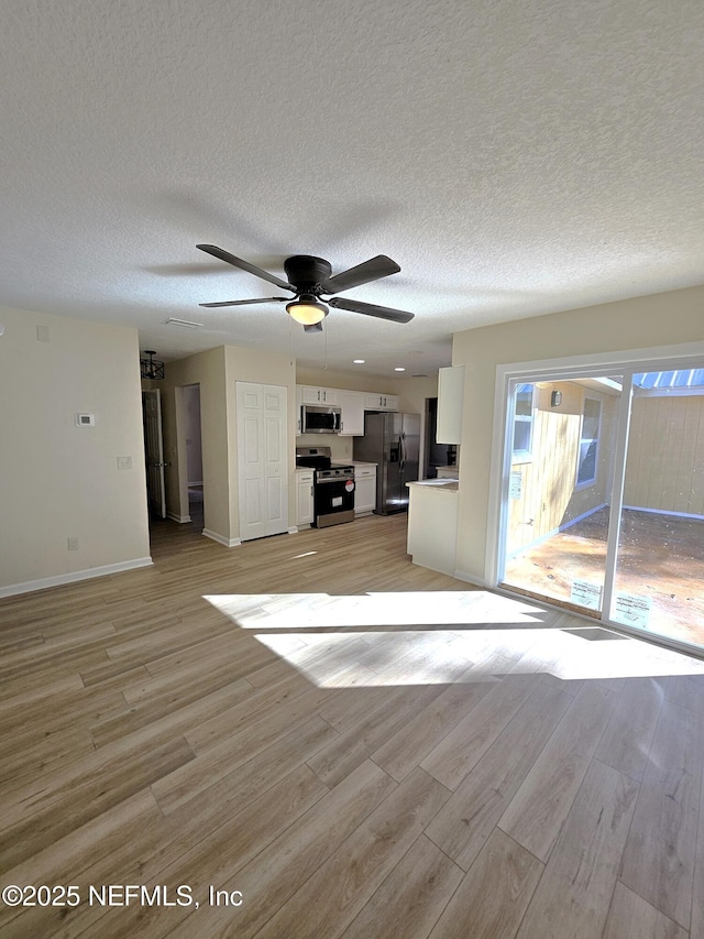 unfurnished living room featuring a textured ceiling, light hardwood / wood-style flooring, and ceiling fan