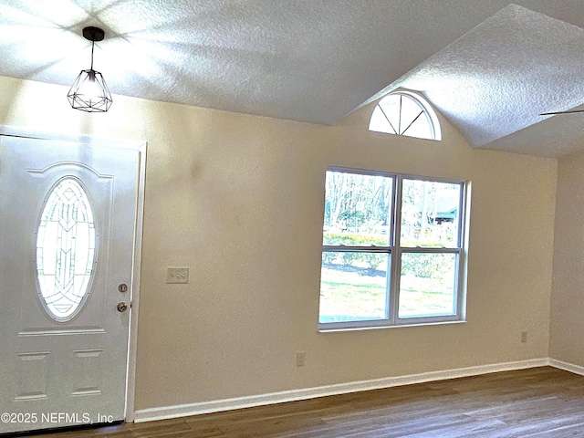 entryway featuring wood-type flooring, lofted ceiling, and a textured ceiling