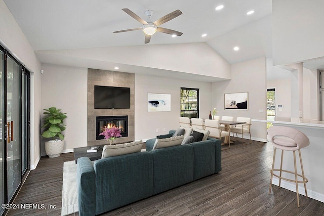 living room featuring dark wood-type flooring, ceiling fan, high vaulted ceiling, and a tile fireplace