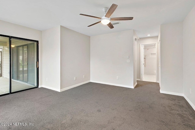 spare room featuring dark carpet and ceiling fan