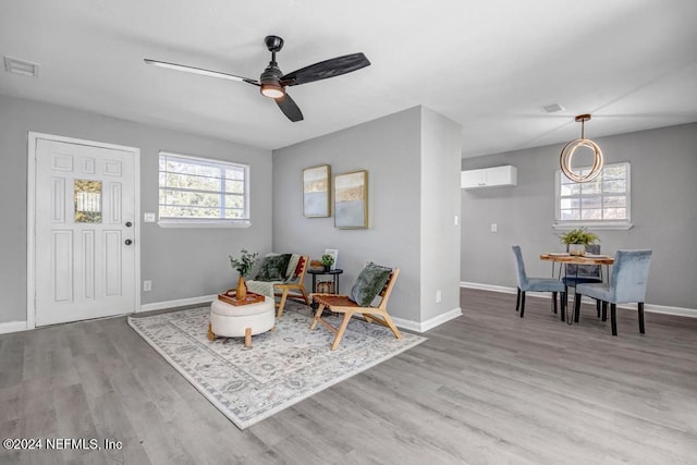 sitting room featuring ceiling fan, a healthy amount of sunlight, light hardwood / wood-style floors, and an AC wall unit