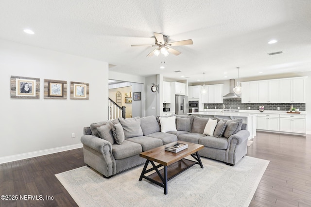 living room with ceiling fan, a textured ceiling, and light wood-type flooring