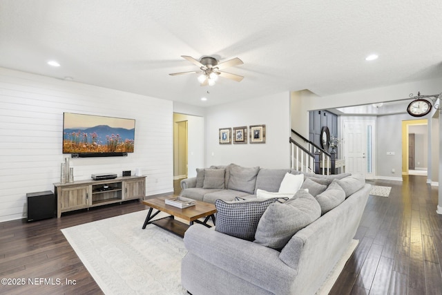 living room featuring ceiling fan, dark wood-type flooring, and a textured ceiling