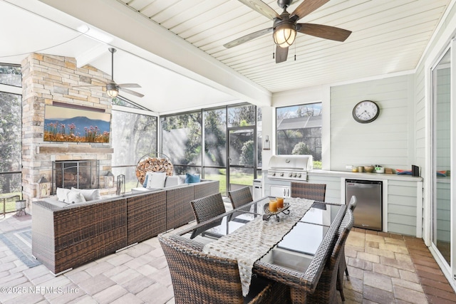 sunroom / solarium with a fireplace, a healthy amount of sunlight, lofted ceiling with beams, and ceiling fan