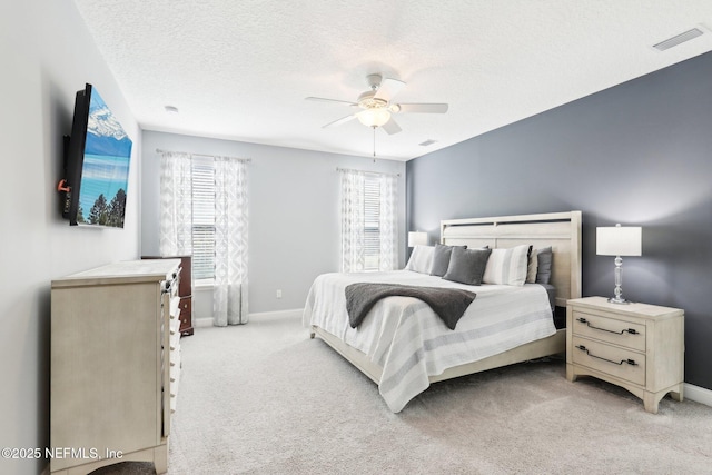 bedroom featuring ceiling fan, light colored carpet, and a textured ceiling