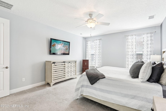 carpeted bedroom featuring multiple windows, a textured ceiling, and ceiling fan