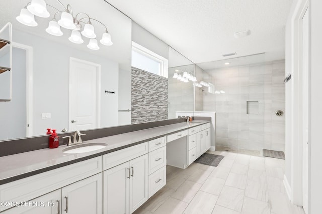 bathroom with vanity, walk in shower, and a textured ceiling