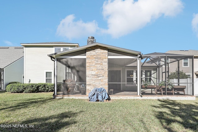 back of house with glass enclosure, a sunroom, a lawn, and a patio