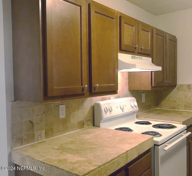 kitchen with white electric stove and tasteful backsplash