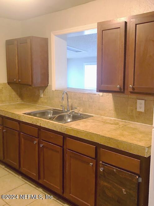 kitchen featuring light tile patterned floors, sink, and tasteful backsplash