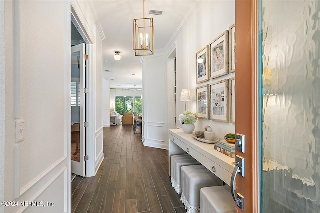 hallway with ornamental molding, dark hardwood / wood-style flooring, and a notable chandelier