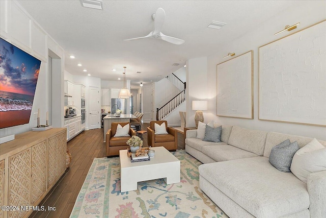 living room featuring dark wood-type flooring and ceiling fan