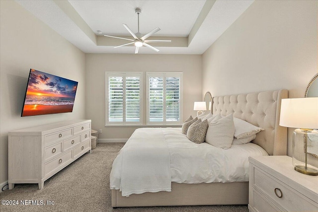 bedroom featuring light carpet, a raised ceiling, and ceiling fan