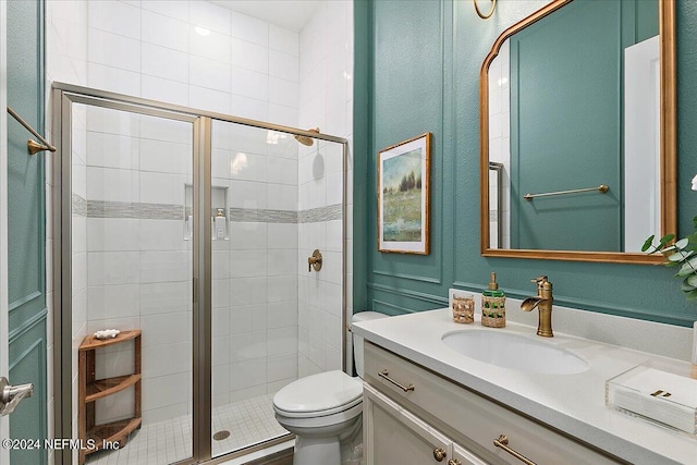 bathroom featuring vanity, toilet, and a shower with shower door