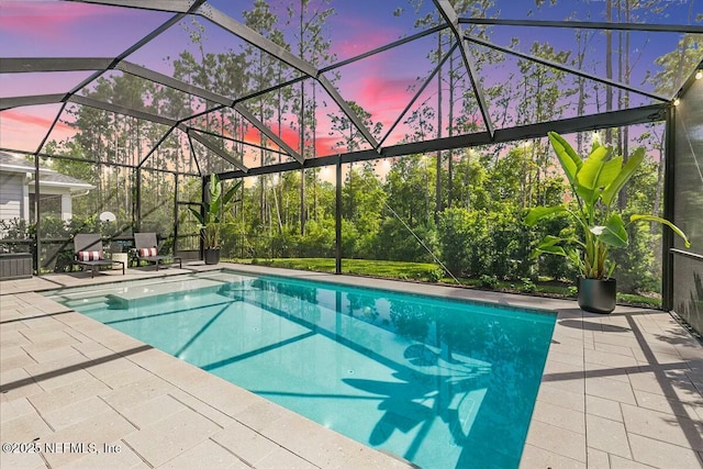 pool at dusk featuring a lanai and a patio area