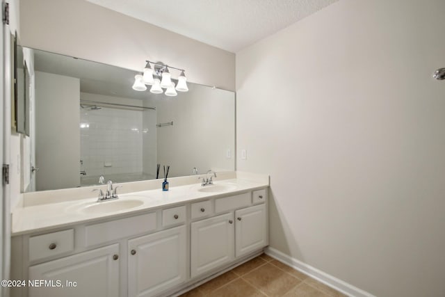 bathroom with tile patterned floors, tiled shower, a textured ceiling, and vanity