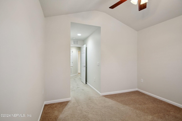 empty room featuring ceiling fan, light colored carpet, and vaulted ceiling