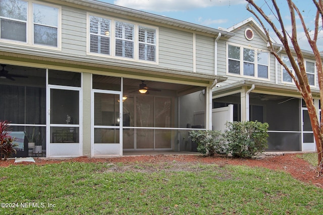 rear view of property with a sunroom, ceiling fan, and a lawn