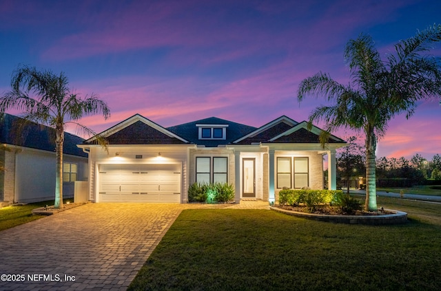 view of front of house featuring decorative driveway, a front lawn, and an attached garage
