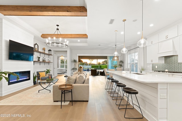 living area featuring crown molding, light wood finished floors, recessed lighting, and visible vents