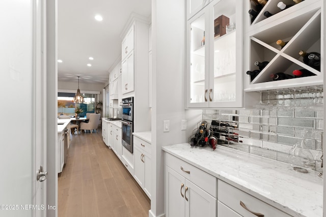 kitchen with recessed lighting, light stone countertops, decorative backsplash, glass insert cabinets, and white cabinets