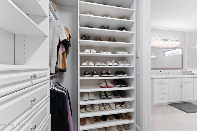 spacious closet with marble finish floor and a sink