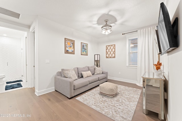living area with visible vents, baseboards, and light wood-type flooring