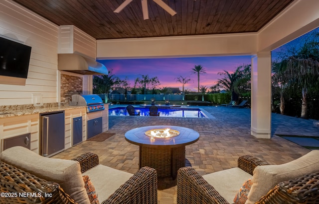 patio terrace at dusk featuring a fenced in pool, exterior kitchen, a fenced backyard, area for grilling, and a ceiling fan