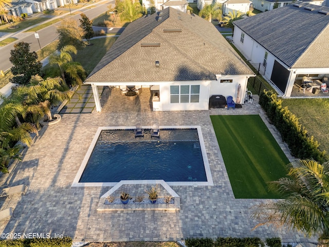pool featuring fence, a patio area, and a lawn