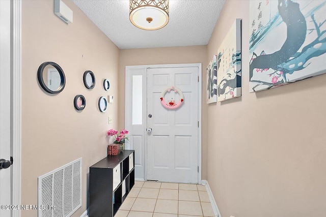 doorway to outside featuring light tile patterned floors and a textured ceiling