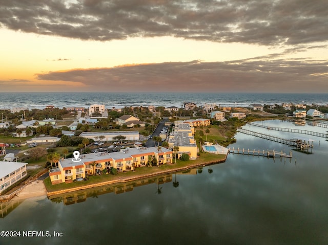 aerial view at dusk featuring a water view