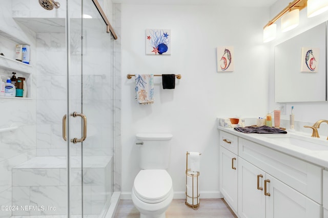 bathroom featuring vanity, toilet, and a shower with shower door