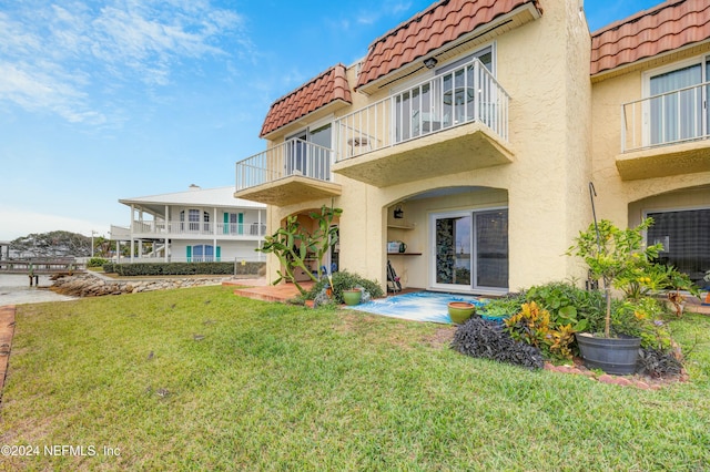 back of property featuring a patio, a balcony, and a lawn