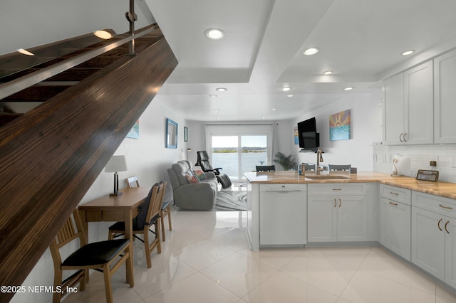 kitchen featuring white dishwasher, sink, tasteful backsplash, and white cabinets