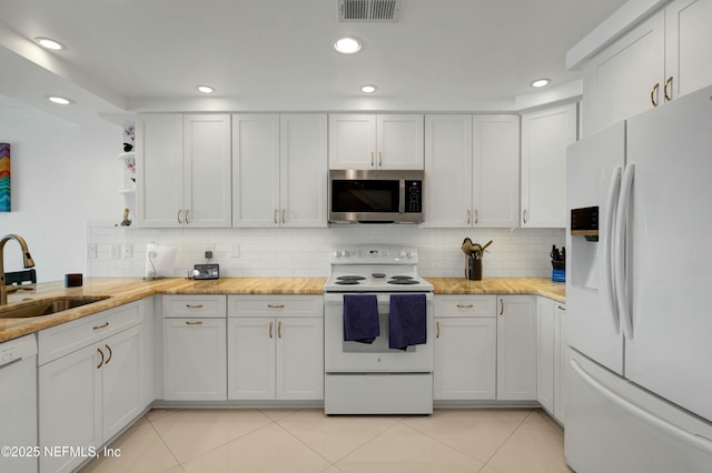 kitchen featuring sink, white cabinets, and white appliances