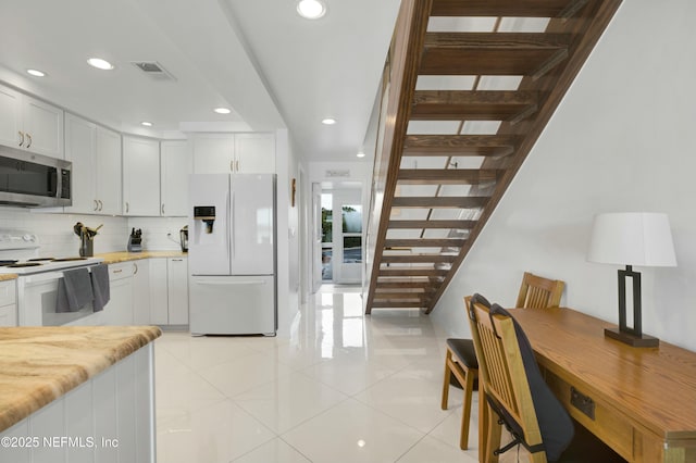 kitchen featuring backsplash, white cabinets, white appliances, and light stone counters