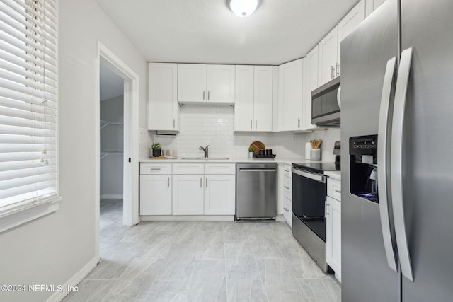 kitchen featuring white cabinets, decorative backsplash, stainless steel appliances, and sink