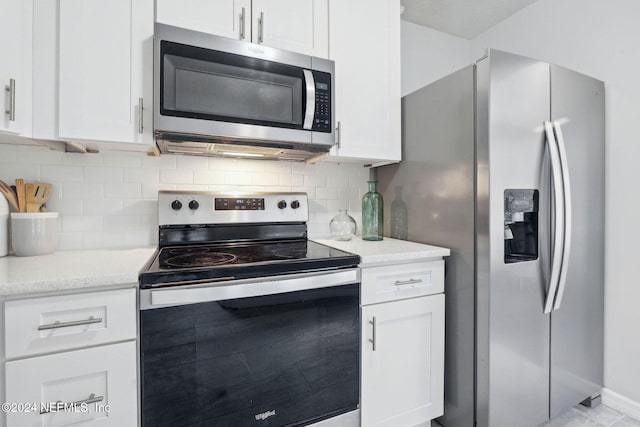 kitchen with light stone countertops, stainless steel appliances, and white cabinetry