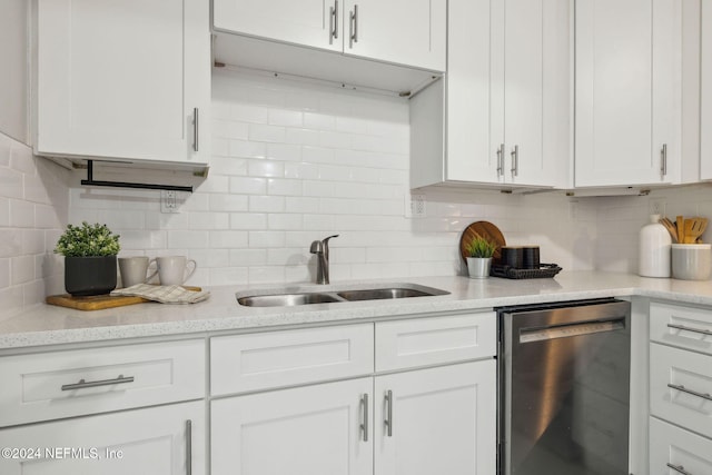 kitchen featuring stainless steel dishwasher, sink, white cabinetry, and backsplash