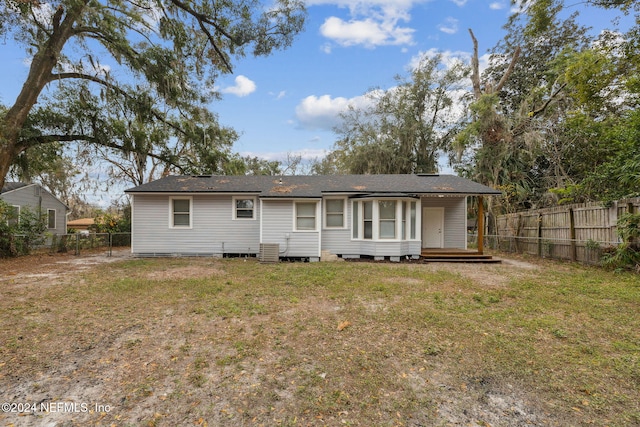 back of property with a wooden deck and a lawn