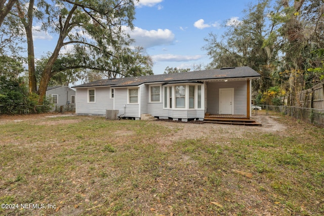 rear view of house featuring a deck, a yard, and central AC