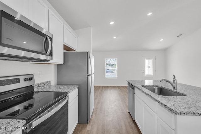 kitchen with light stone countertops, light wood-type flooring, stainless steel appliances, sink, and white cabinets