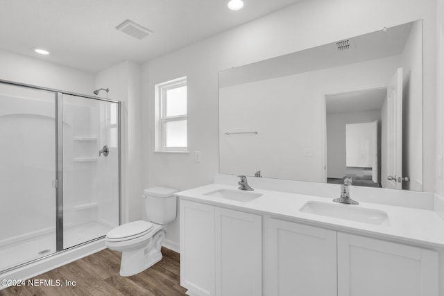 bathroom with wood-type flooring, vanity, toilet, and a shower with shower door