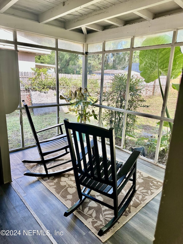 sunroom / solarium featuring beamed ceiling, plenty of natural light, and wood ceiling