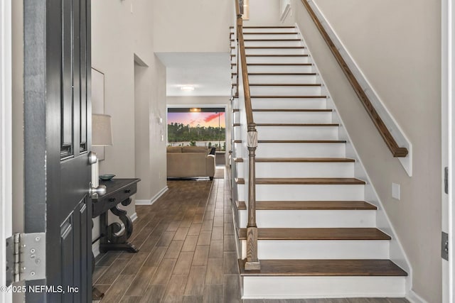 staircase with hardwood / wood-style flooring and a high ceiling