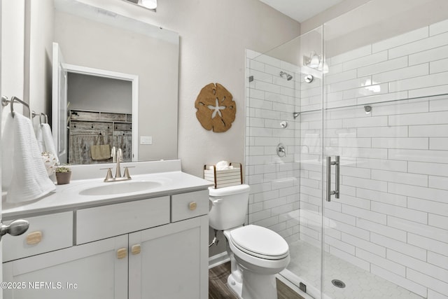 bathroom featuring a shower with door, vanity, wood-type flooring, and toilet